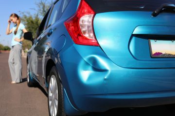 Driver upset after a fender bender dent in blue car bumper