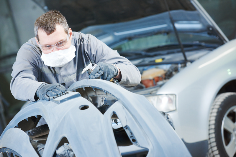 Auto body repair technician sanding a bumper to prep for paint.