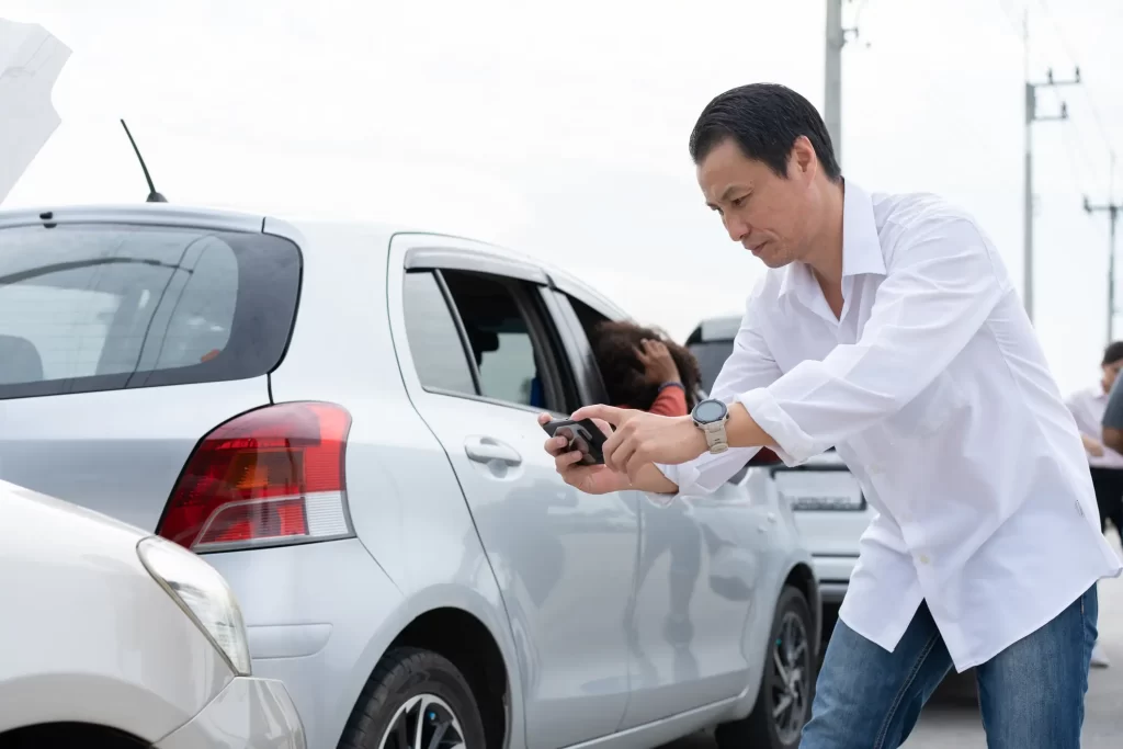 Driver taking photos of vehicle damage after a car accident in Lewisville, TX