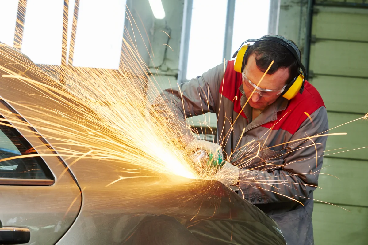 Auto body repair technician working on a damaged vehicle panel in Lewisville TX
